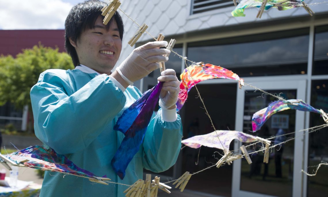 student clips tie dye to drying line