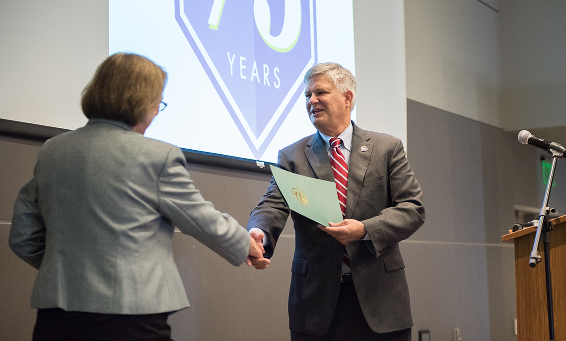 Lakewood Mayor Don Anderson shakes hands with Clover Park Technical College President Dr. Joyce Loveday and hands over a copy of the city's proclamation honoring the college.