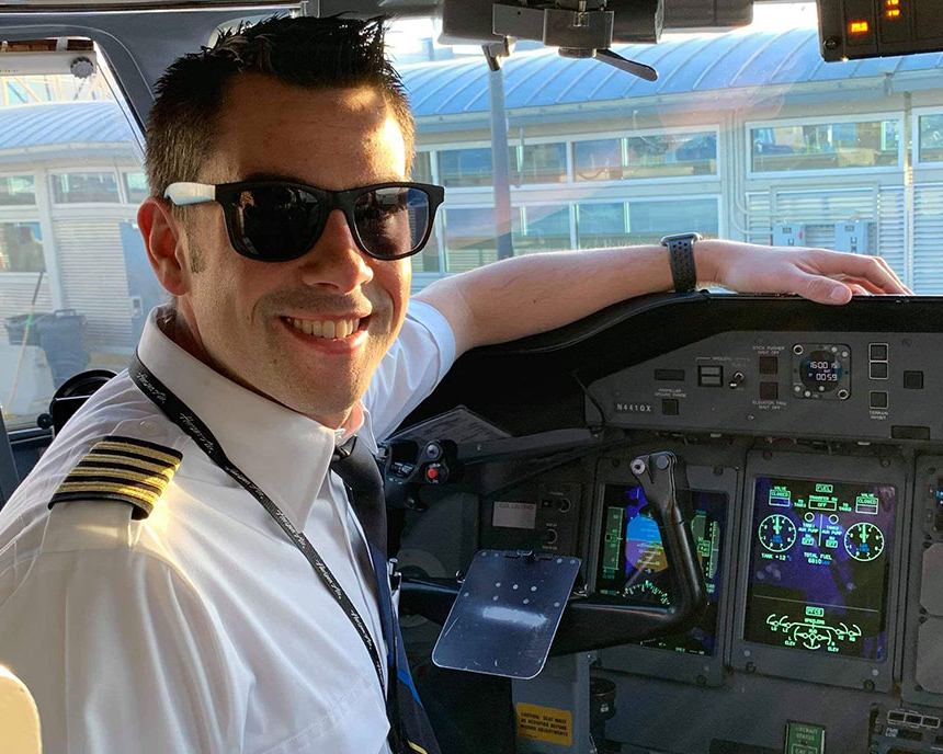 Man in pilot uniform sits in airplane cockpit