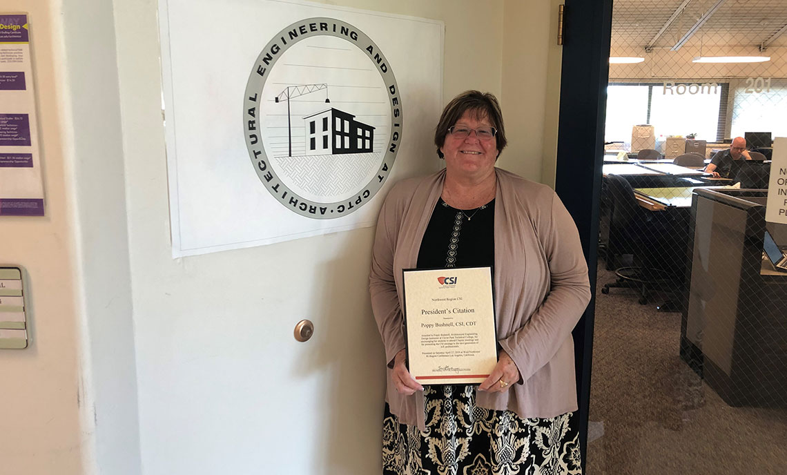 Women holds award in front of program sign