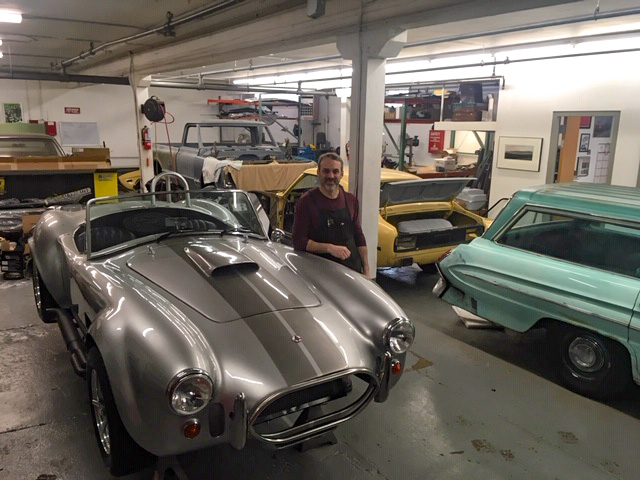 Any Osborn standing with classic cars in the garage of his business.