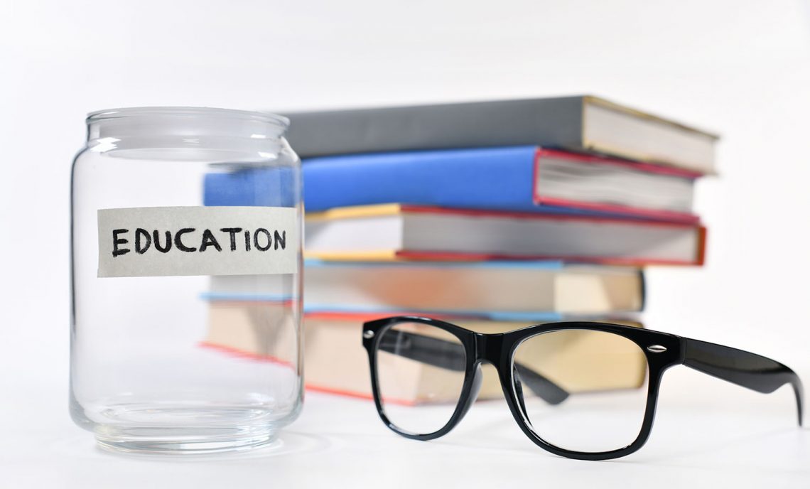 stack of books, glasses, empty jar with label says education