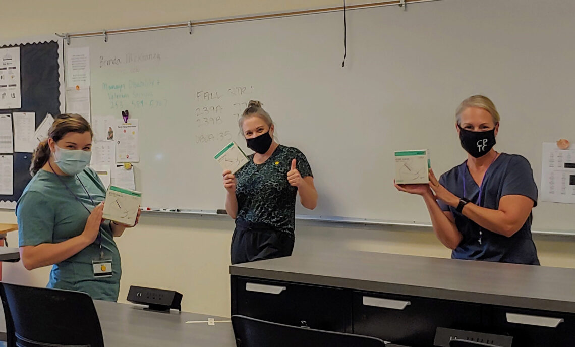 threee students wearing masks holding their donated N95 masks