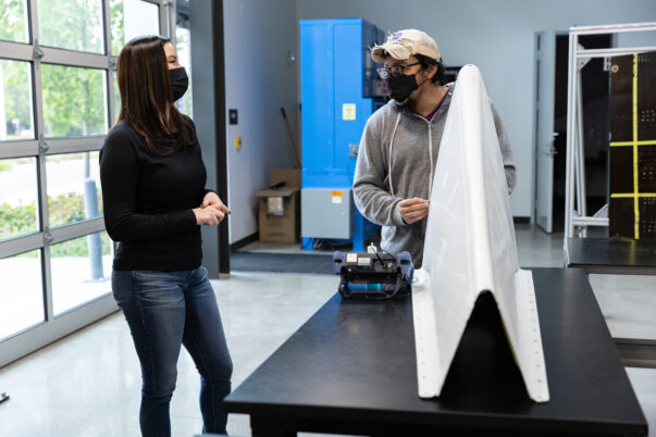 Megan Davey on the left with student holding a white wing shaped object on the left