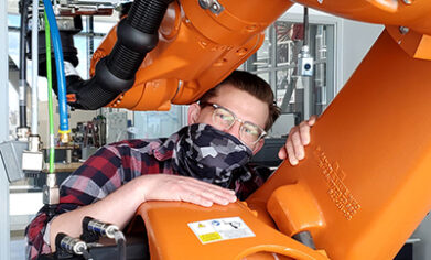 masked student posing in a robotic arm