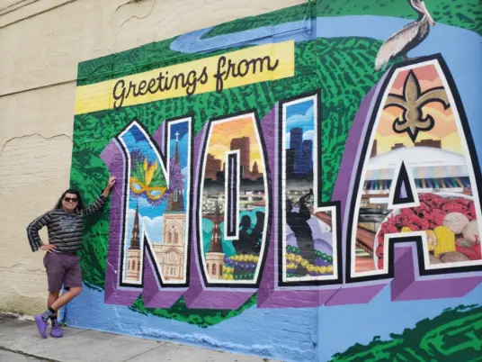 Luke Ruiz standing in front of a large mural in New Orleans, LA.