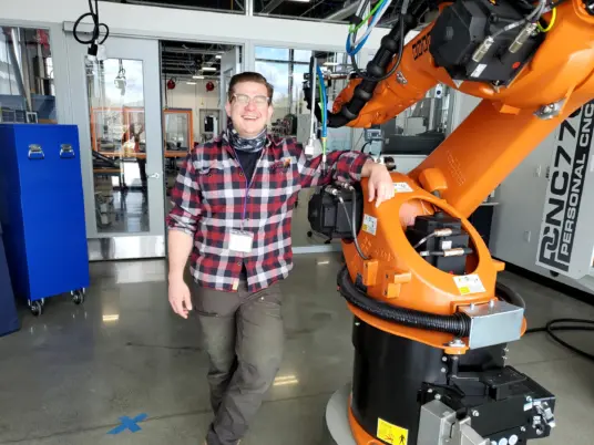 Advanced Manufacturing Instructor Carl Wenngren poses with CPTC's KUKA robotic arm in Building 24